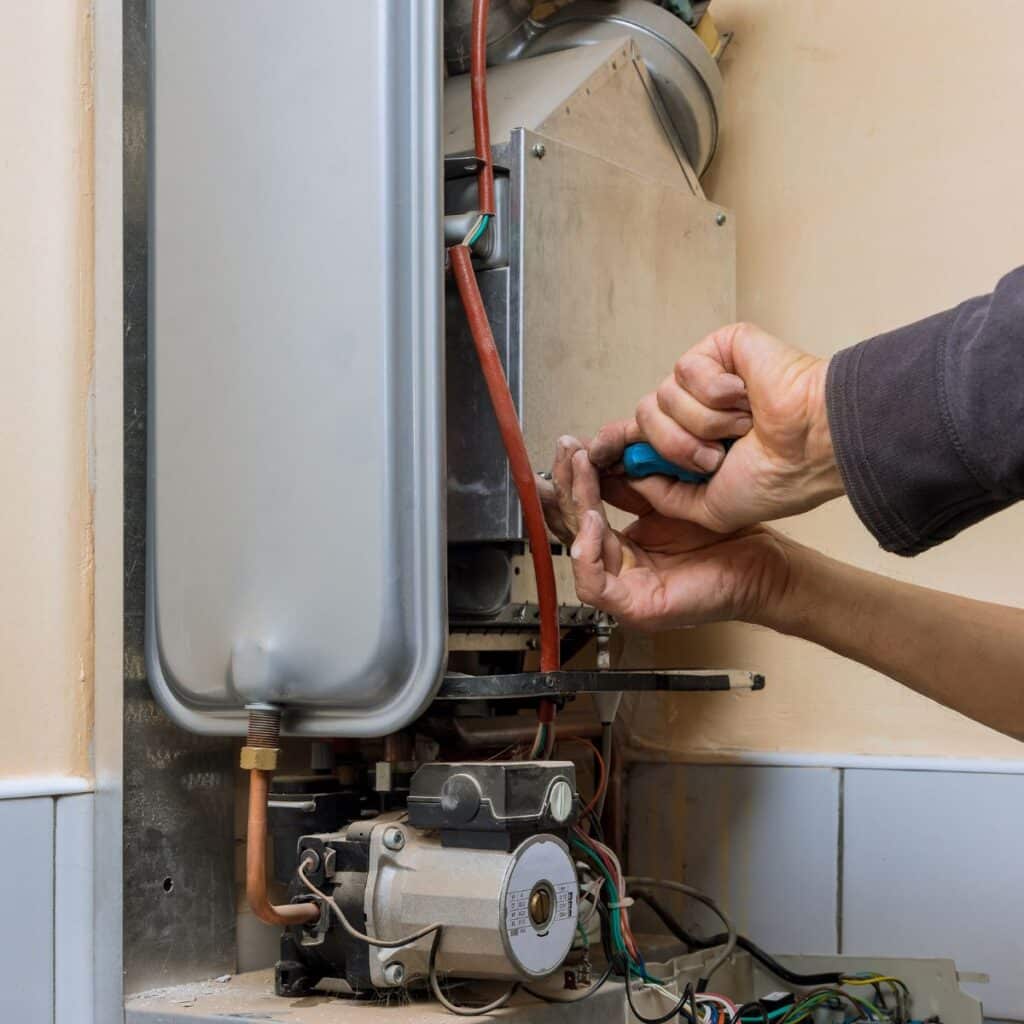 tech repairing a furnace using pliers