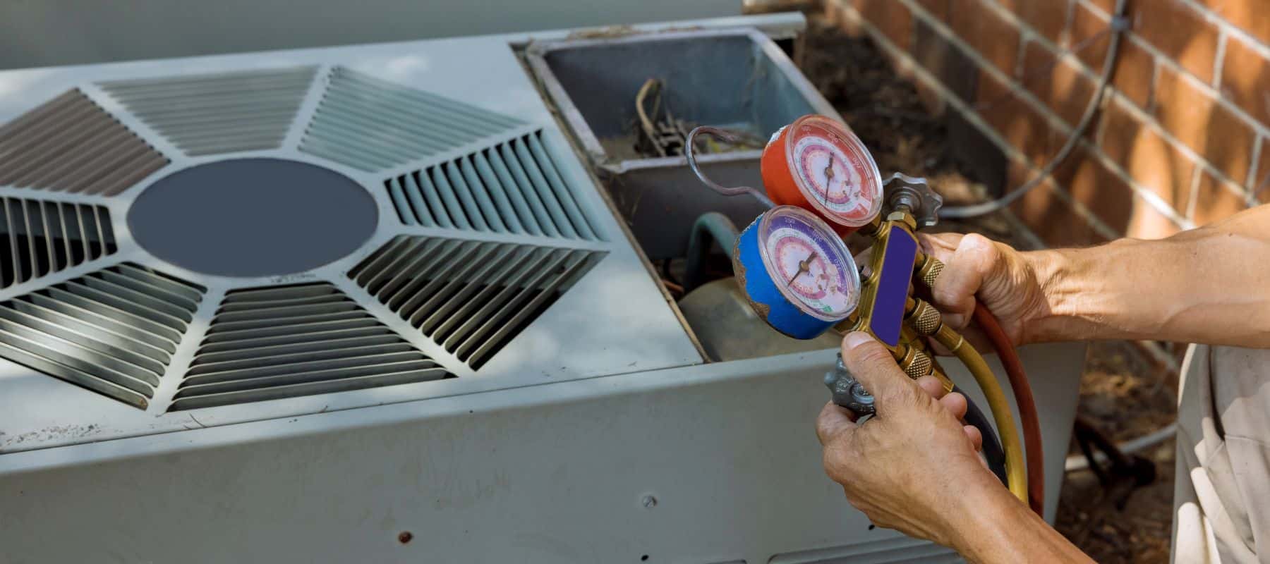hvac tech reading his gauges to check the levels in an ac unit
