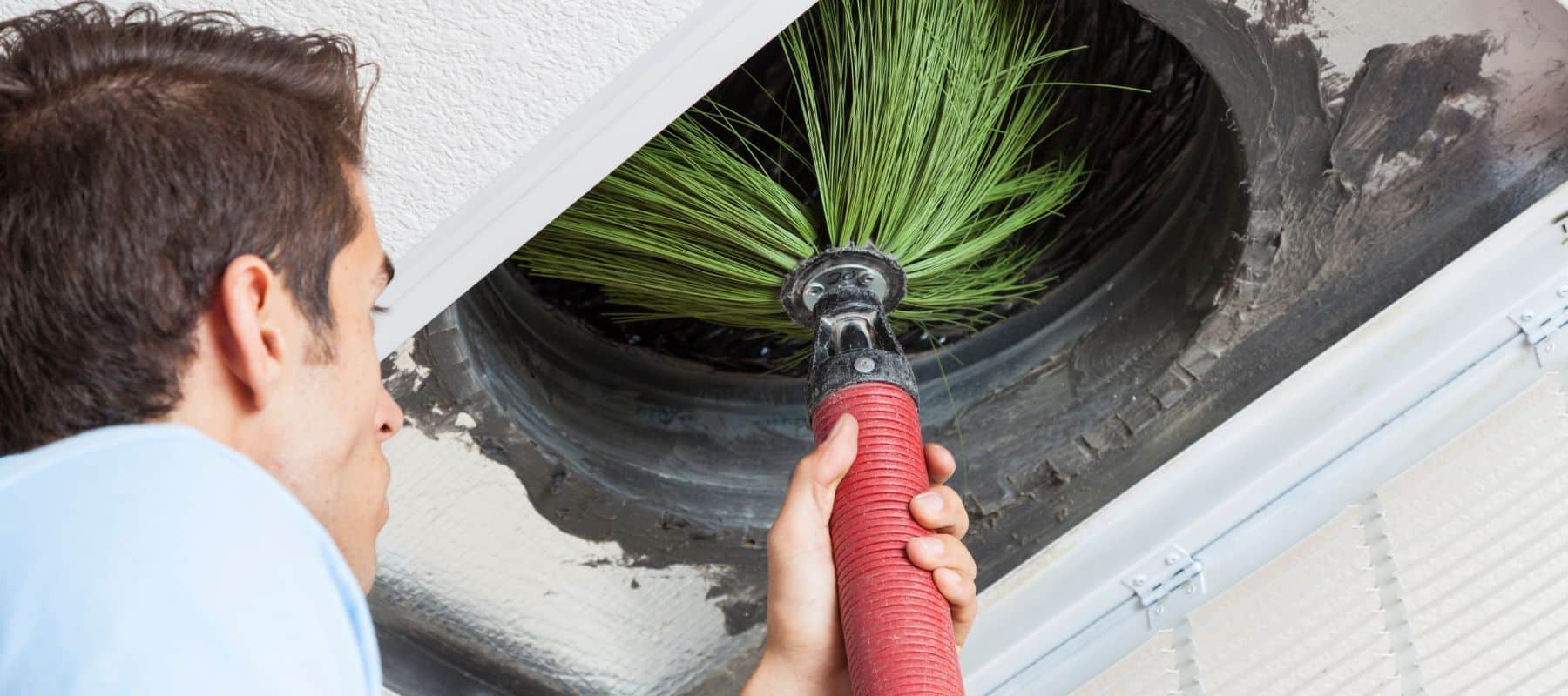 hvac tech using a vacuum brush to clean out a dusty air duct